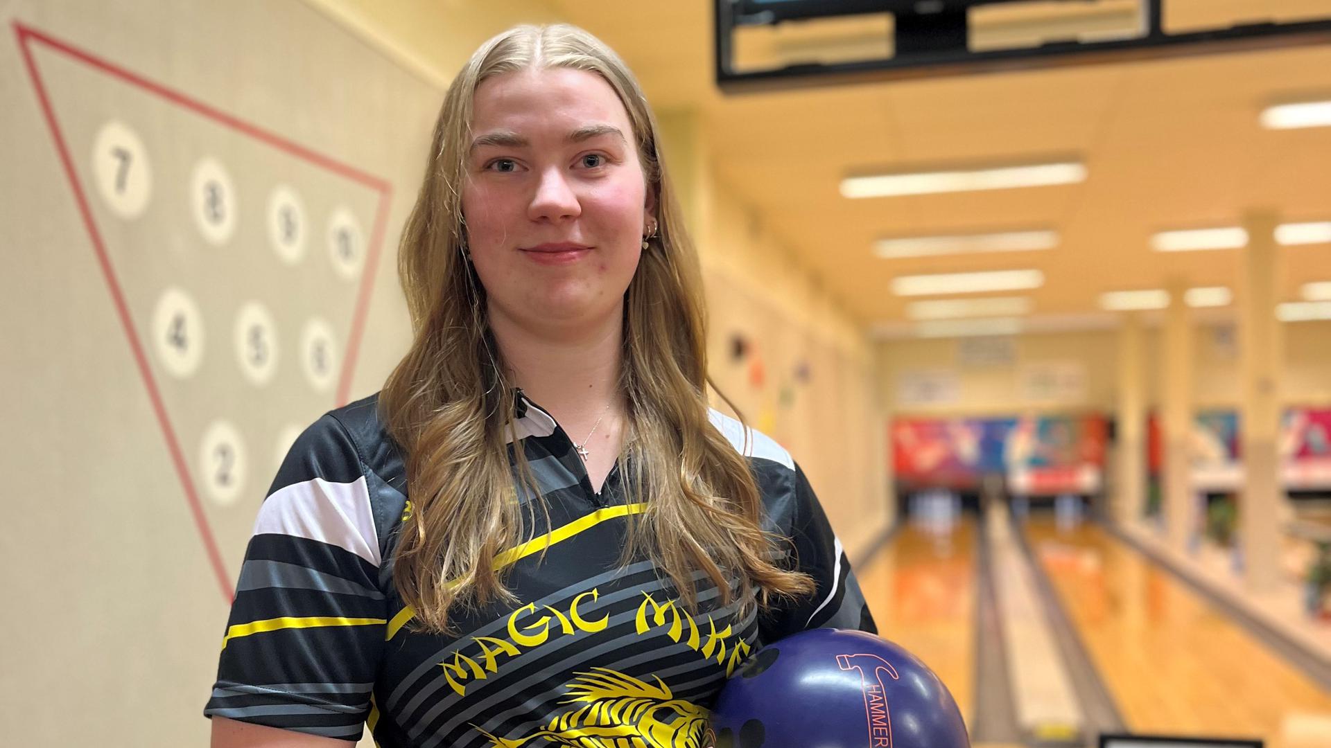 En kvinna står med ett bowlingklot i famnen